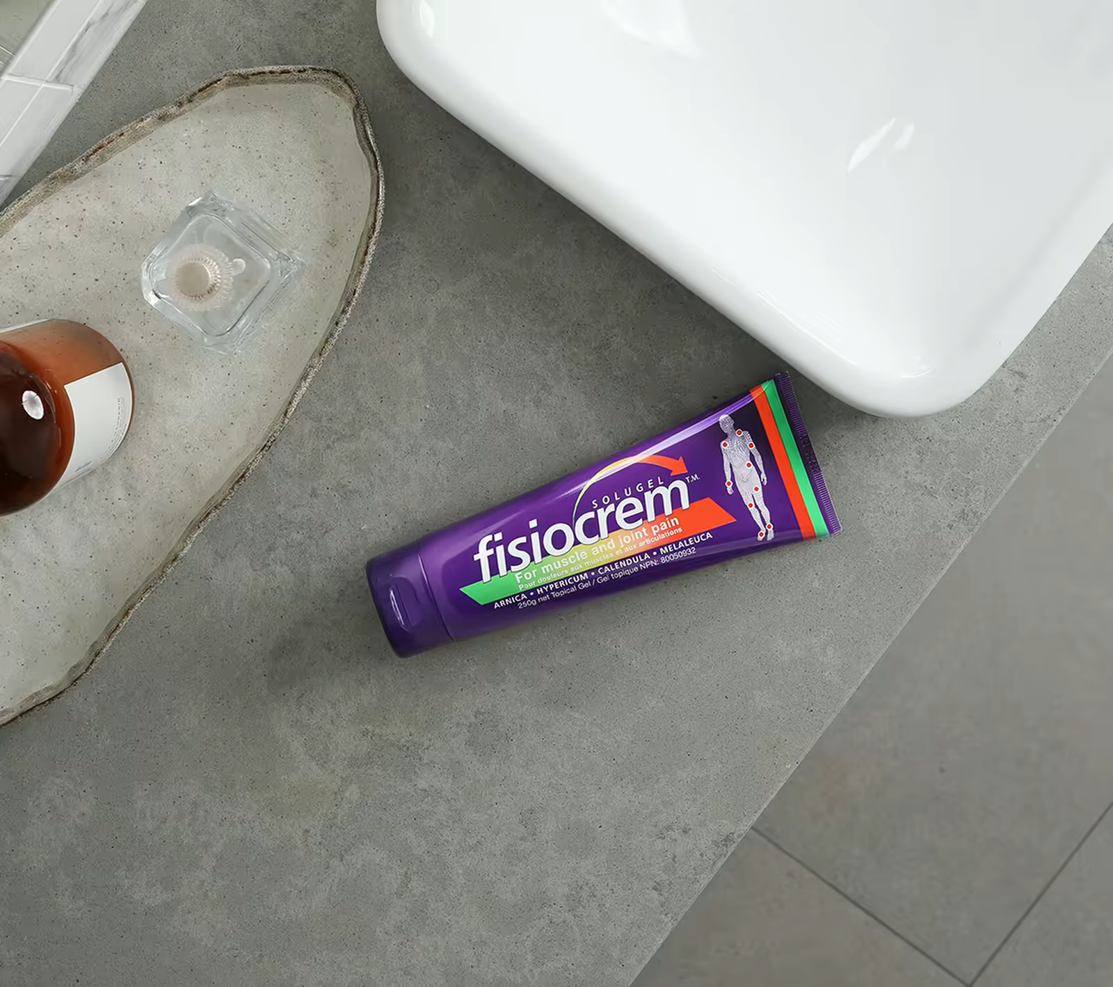 Fisiocrem tube lying on a stone tile floor next to a white sink