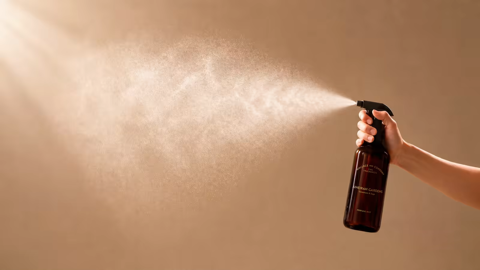 Hand spraying Wallace & Company perfume mist in a beam of light